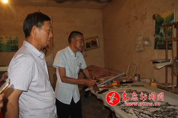 王平貴和他的老朋友村支部書記徐文富探討如何完成這幅畫作。.JPG